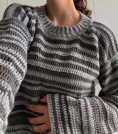 a woman is wearing a gray sweater and has her hands on her hips