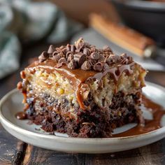 a piece of cake on a plate covered in chocolate chips and caramel drizzle