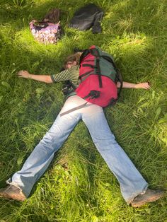 a person laying in the grass with a backpack on their back