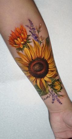 a sunflower tattoo on the arm with purple and orange flowers around it's center