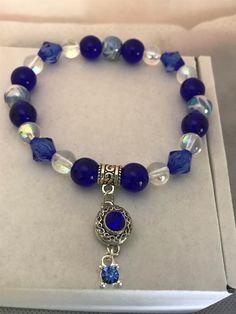 a bracelet with blue glass beads and a silver plated charm is displayed in a box