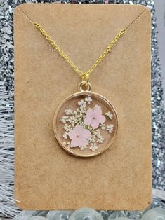 a necklace with pink flowers on it sitting on top of a piece of brown paper