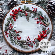 a christmas wreath with red berries and pine cones is featured in this hand embroidery pattern