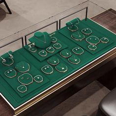 a green table topped with lots of jewelry on top of a hard wood floor next to a black chair