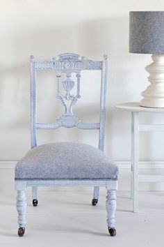 a blue chair sitting next to a white table with a lamp on top of it