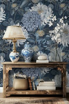 a blue and white floral wallpaper in a living room with a lamp on the side table