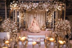 the bride is walking down the aisle with her wedding dress on and candles in front of her