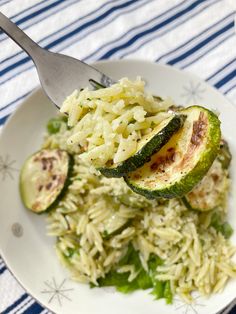 a white plate topped with rice and zucchini on top of a blue and white table cloth