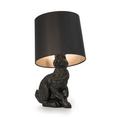 a black lamp with a cat sitting on it's side next to a black shade