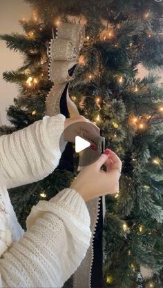 a woman is decorating a christmas tree with ribbon and lights on the trees branches