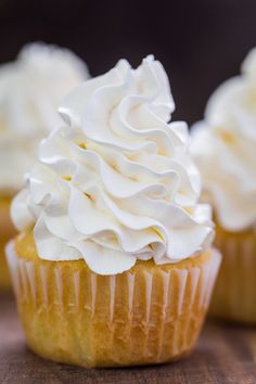 three cupcakes with white frosting sitting on a table