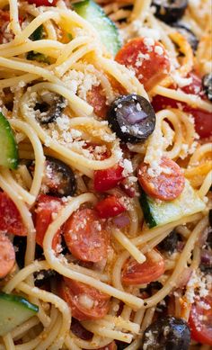 a close up view of a pasta salad with tomatoes, cucumbers and olives