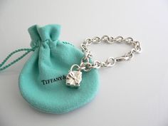 Offered for sale is a wonderful and super cute Tiffany and Co. Sterling Silver Signature Gift Box Charm bracelet.   The piece is made from substantial and bright Tiffany silver, and yet retains a very feminine feel to it.  Attached to its very substantial and bright Tiffany Silver charm bracelet is a super Cool Signature Gift Box Padlock charm.  The Gift Box padlock charm is permanently attached to the bracelet - so you will not ever have the risk of losing the charm!  It is a classic Tiffany pi Designer Rectangular Bracelets As Gift, Luxury Rectangular Bracelet As Gift, Luxury Rectangular Bracelet Gift, Elegant Rectangular Jewelry For Birthday Gift, Luxury Silver Jewelry In Gift Box, Designer Silver Jewelry With Original Box, Designer Silver Jewelry In Original Box, Luxury Silver Jewelry With Original Box, Luxury Silver Jewelry For Birthday Gift