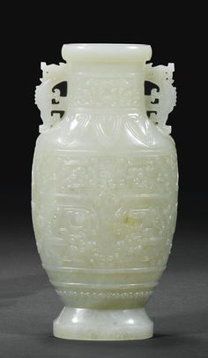 a white vase sitting on top of a black table next to a gray wall and floor