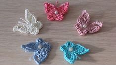 four crocheted butterflies on a table with pearls in the middle and one has a pearl beaded center