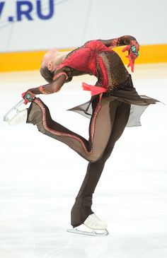 a figure skating on an ice rink wearing a red and black outfit