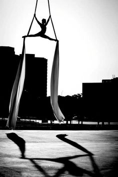 a person doing aerial tricks in the middle of an open area with tall buildings behind them