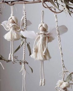 three white angel ornaments hanging from a branch