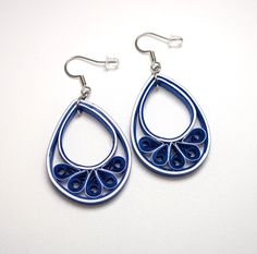 a pair of earrings with blue and white designs on them, hanging from silver hooks