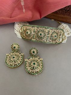 A beautiful green jadau choker set string in tiny white beads will set you apart. This high quality trendy jewelry set is a must have in your collection.  The Jadau workmanship was introduced by the Mughals and is now practiced and perfected by the skilled craftsman of Rajasthan in India.  Details: Necklace Width-1.5 Inches Earrings Length-2.25 Inches Weight of Each Earring-12 gms All products are manufactured using traditional skills from our rich heritage of crafts.  The process of these craft Green Kundan Temple Jewelry Set, Adjustable Kundan Jewelry With Zari Work, Green Temple Jewelry Bridal Sets For Ceremonial Occasion, Green Temple Jewelry Bridal Set For Ceremonial, Green Temple Jewelry Bridal Set For Ceremonial Occasions, Elegant Green Cutdana Choker, Green Kundan Ceremonial Sets, Adjustable Festive Jewelry With Zari Work, Ceremonial Green Kundan Sets