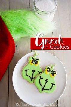 two decorated cookies sitting on top of a white plate next to a green elf hat