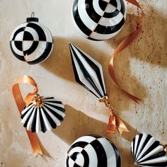 black and white ornaments with gold ribbons on a marble surface, including an ornament in the shape of a fan