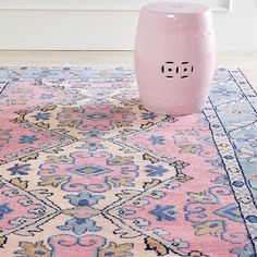 a pink stool sitting on top of a rug