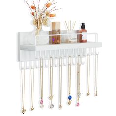 a white wall mounted shelf with jewelry hanging from it