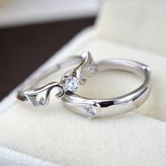 two wedding rings sitting on top of a white cloth covered cushioned surface with snowflakes in the background