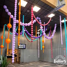 balloons are hanging from the ceiling in an airport lobby, decorated with multicolored streamers