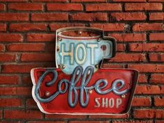 coffee shop sign on the side of a brick wall with a cup and saucer