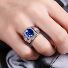 a woman's hand wearing a ring with a blue stone in the center and diamonds around it