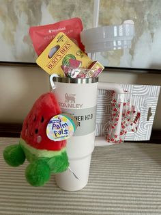 a watermelon stuffed animal sitting in a coffee cup filled with tea and candy