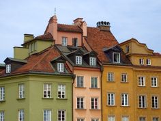 many different colored buildings with windows on top of each one in front of a blue sky