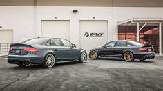 two cars parked next to each other in front of a building with garage doors open