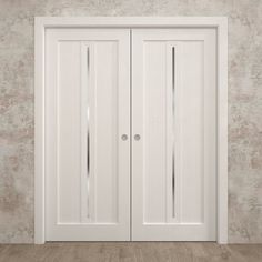 an empty room with two white doors on the wall and wood flooring in front of it