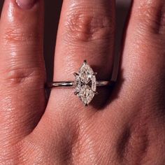 a woman's hand with a diamond ring on top of her finger, showing the center stone