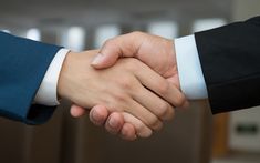 two people shaking hands in front of each other