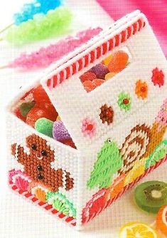 a small white box filled with lots of candies on top of a pink table