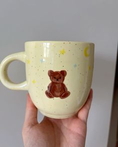 a hand holding a coffee cup with a teddy bear on it