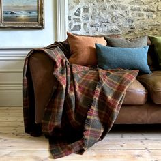 a couch covered with blankets and pillows in front of a stone wall, next to a brick wall