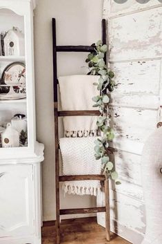 an old ladder is used as a towel rack in this shabby white bathroom with greenery