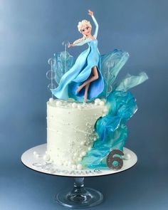 a frozen princess cake with blue icing and white frosting on the top tier