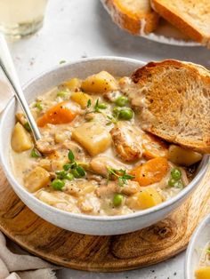 a bowl of chicken and vegetable soup with two slices of bread on the side