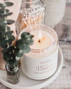 a candle sitting on top of a white plate next to a potted plant