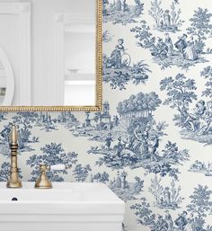 a white sink sitting under a mirror next to a wallpaper covered in blue and white