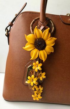 a brown handbag with yellow flowers on the handle and tag hanging from it's strap