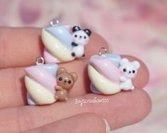 three tiny teddy bears sitting on top of a white and blue object in someone's hand