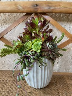 a white vase filled with lots of green plants