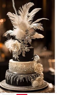 a black and white wedding cake decorated with feathers, flowers and diapaste beads